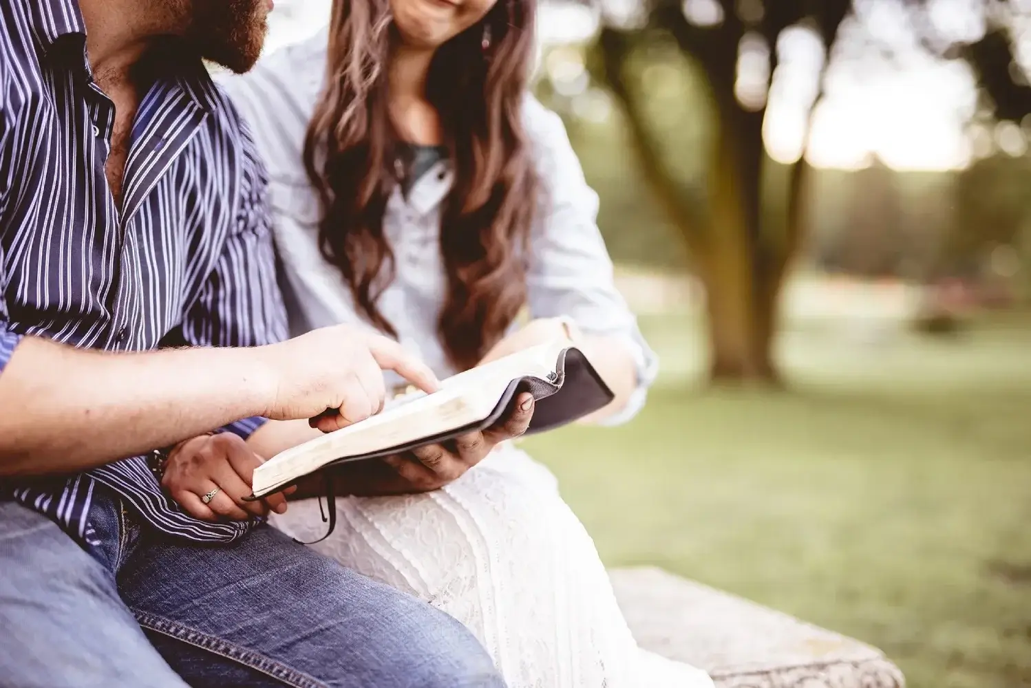 Closeup shot of a couple sitting and reading the bible